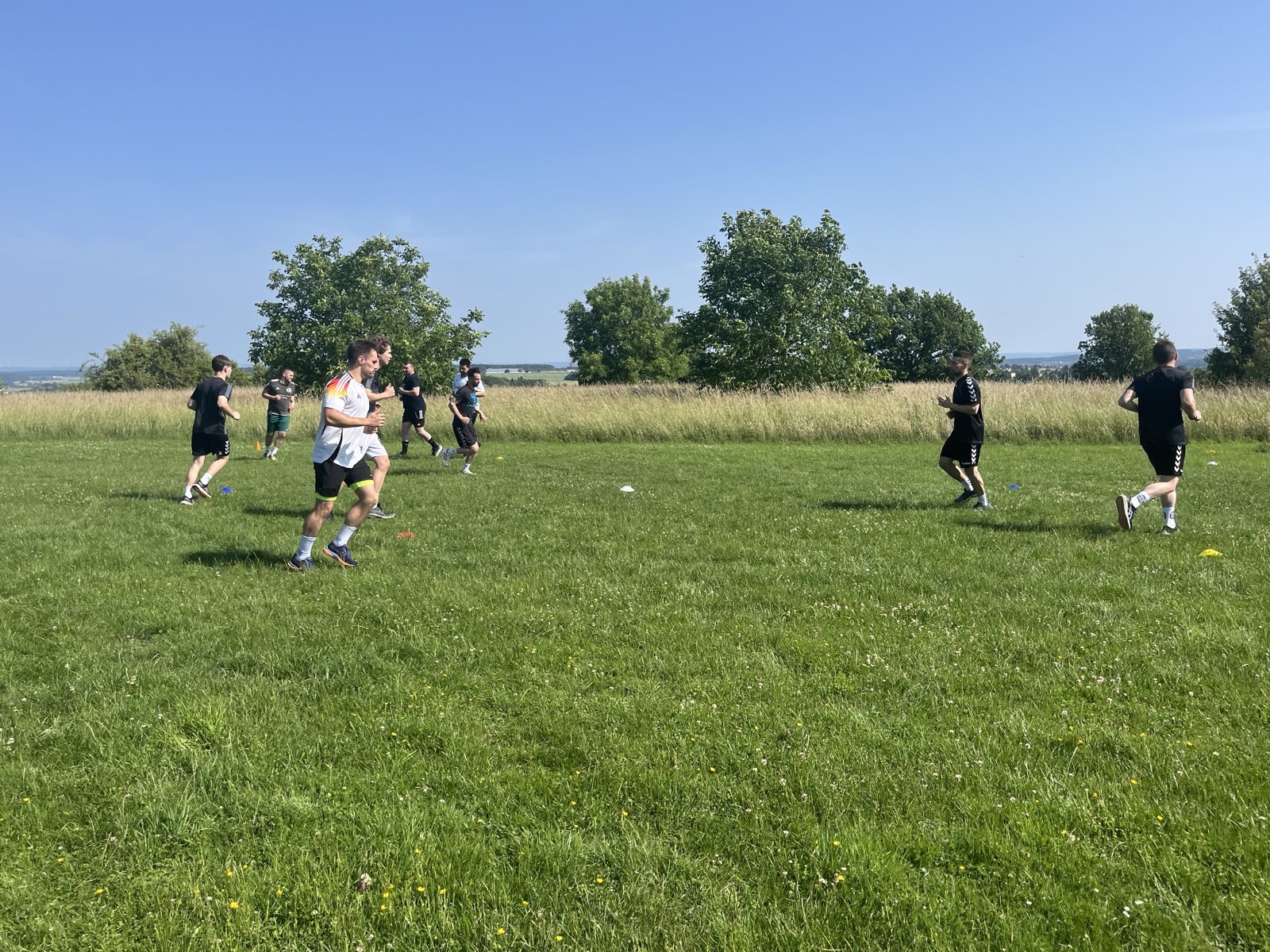 Mannschaft läuft im Sonnenschein über die Wiese