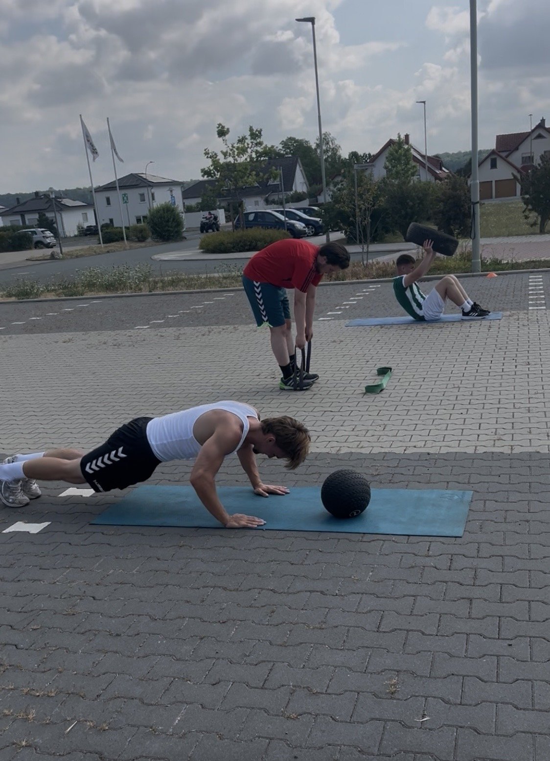 Teilnehmer in der Plank mit Medizinball, Gruppe im Hintergrund